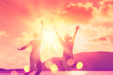 Women jumping on tropical beach with sunset sky and island background. Freedom and feel good...