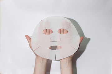  Sheet face mask. Fabric mask for facial skin. Female hands hold a face mask. On a white...