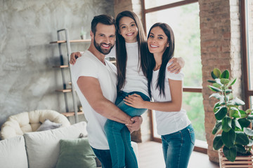 Portrait of nice attractive lovely affectionate sweet careful cheerful family wearing casual white t-shirts jeans carrying pre-teen brunette schoolgirl at industrial loft style interior living-room