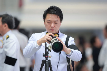 Professional cameraman holding the mirrorless camera with tele len in front of blur crowd background.