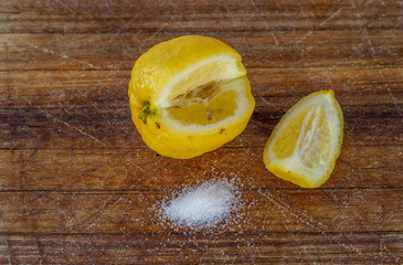 A sliced lemon and some salt on a wooden platter image in horizontal format with copy space