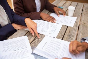Businesspeople discussing agreement terms. Business man and women sitting at cafe table, reading documents and drinking coffee. Paperwork concept - obrazy, fototapety, plakaty