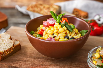 Bowl with tasty boiled legumes, vegetables and sausages on table