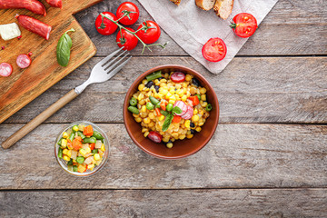 Bowl with tasty boiled legumes, vegetables and sausages on wooden table