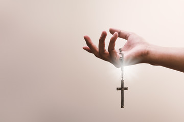 Praying hands hold a crucifix or cross of metal necklace with faith in religion and belief in God...