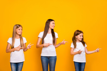Fototapeta premium Photo of charming ladies indicating fingers side empty space wear casual clothes isolated yellow background