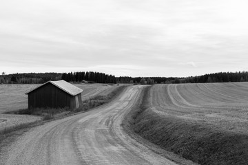Barn on the roadside. Countryside road. Image in black and white.