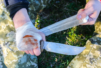 Man is putting bandage on bleeding wound. Injured hand. Cut with a knife. Tourist in the nature....