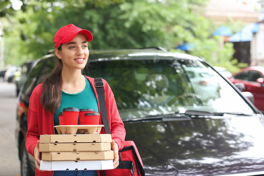 Female worker of food delivery service near car outdoors