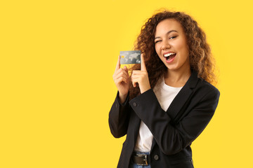 Beautiful African-American woman with credit card on color background