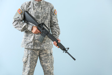 Soldier with assault rifle on color background