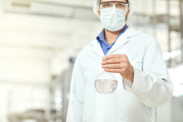 The hands of a man holding a flask with test water