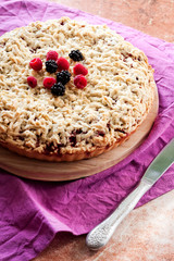 Homemade shortcrust berry pie with crumble on wooden board