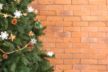 Beautiful Christmas tree against brick wall, closeup