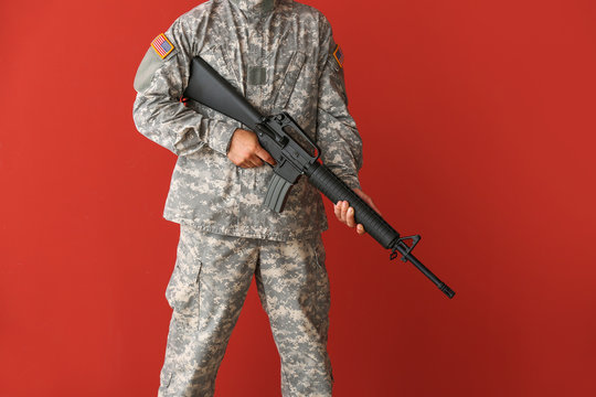 Soldier with assault rifle on color background