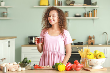 Beautiful African-American woman cooking in kitchen