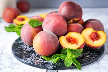 Board with tasty peaches on table