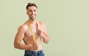 Handsome muscular man with measuring tape on color background. Weight loss concept