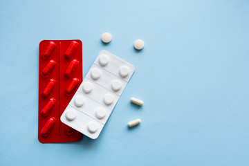 Medicine capsules and tablets  in red and white blister packs on a blue background. Isolated. Copy space.