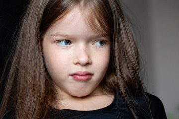 portrait of a pensive sad girl with long hair on a dark background