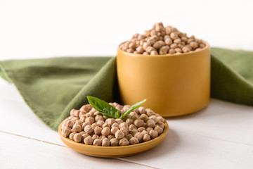 Plate and container with raw chickpea on table