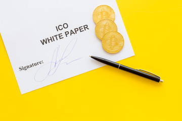 Initial coin offering ICO white paper, bitcoin, pen on yellow background top view