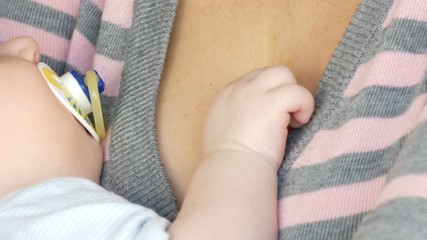 Little hand of a newborn baby of two months on the breast of the mother