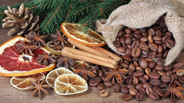 Christmas background. roasted coffee beans in a sack, dried citruses and spices on a wooden table.