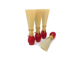 Double reed for bassoon with red thread on a white background. Four mouthpieces for wind musical instruments. With a slight shadow.