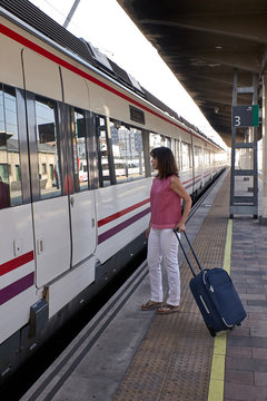woman waiting for the train with a suitcase