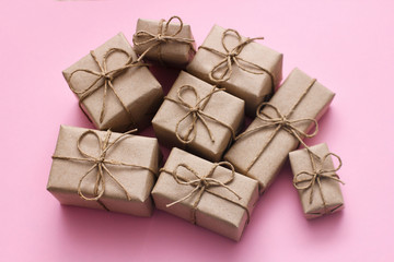 Set of many present boxes wrapped in brown craft paper and tie cord. Pink background texture. Delivery parcels. Gift shop concept.