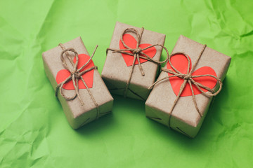 Set of gift boxes. Present wrapped in craft paper and tie hemp cord. Heart carton card. Green crumpled paper background. 