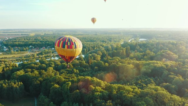 Beautiful scene of the balloon gaining height above a public park or forest. Hot air balloon flies in the sky among other balloons. Summer sunset 4k