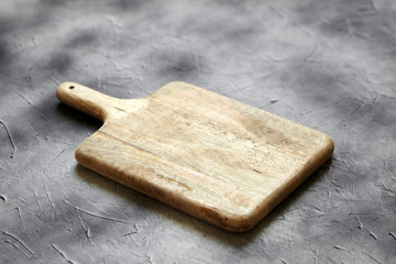 Empty cutting board from pine wood on  stone table, grey background, side view