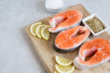 fresh fish. fresh salmon steaks with lemon, spices and salt on a cutting board.