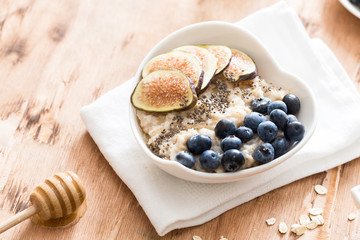 white Bowl of oats porridge with figs, blueberries and chia seeds. Healthy oatmeal breakfast