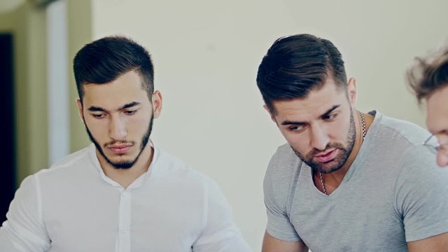 Several young men preoccupied in discussion by perplexity and surprise on their faces