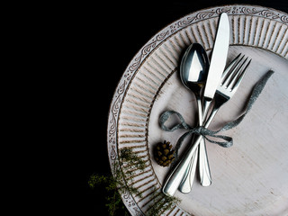 Vintage or rustic christmas table setting Elegant white plate, cutlery and natural pine tree branch...