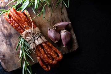 Rural meat. Thin sausages with garlic and herbs on a dark background - obrazy, fototapety, plakaty