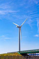 single realistic windmill near the road on blue sky background