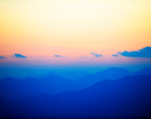 sunrise above layers of mountains