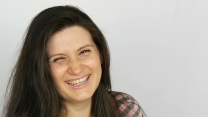 Young beautiful woman with long dark hair and brown eyes of thirty years sincerely laughs and posing for the camera in the studio on a white background.