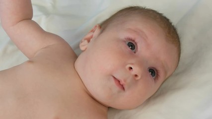 Portrait of beautiful funny little newborn baby of two months lying on a white bed