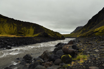 The river flows through the mountains. Gloomy gray sky. Typical Icelandic landscape. Iceland. Vintage hipster look.