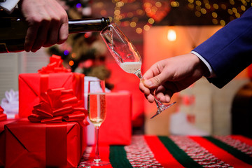 Drink champagne or sparkling wine. Celebrate holiday with champagne. Happy new year. Hands pouring champagne into elegant glass christmas decorations background. Last minute before new year