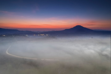 Mountain view misty morning of top hill around with ocean of mist with red sun light and cloudy sky background, sunrise at Khao Takhian (takian) Ngo, Khao Kho, Phetchabun, Thailand.