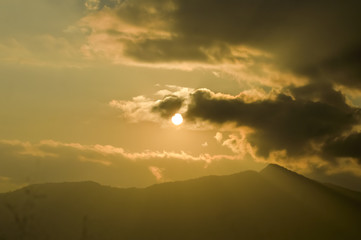 Dramatic dark heavily Red sunset clouds makes the sky romantic on one evening in Mid December. Sunlight reflection while flying passing rolling moving mountain range hill station of India. Silhouette