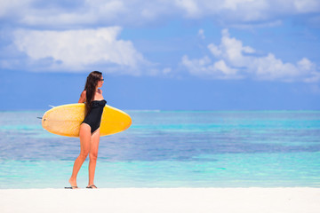 Happy young surf woman at the beach with a surfboard