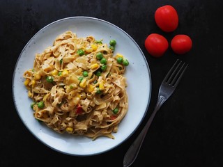 Tagliatelle paste with vegetarian stew on dark background