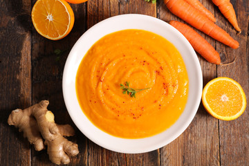 carrot, orange and ginger soup on wood background